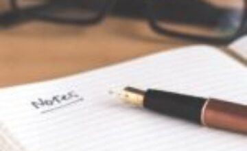 Person writing in a notebook while reflecting on practical support needs