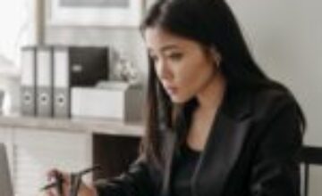 Asian adult beginning a short work task with a notebook and laptop