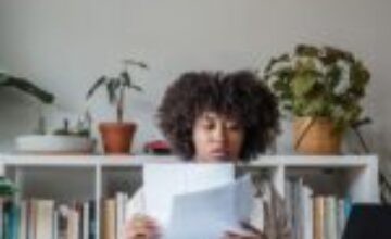 An adult reviewing documents beside a laptop in a calm home office
