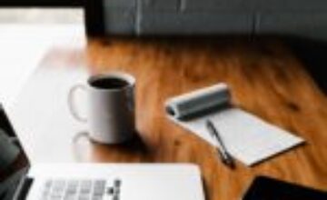 An organised workplace desk with noise-cancelling headphones and a digital task planner.
