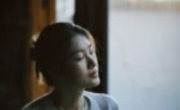 Woman sitting quietly by a window in soft natural light